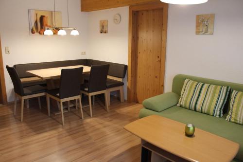 sala de estar con mesa y sofá verde en Ferienwohnung Claudia, en Fügenberg