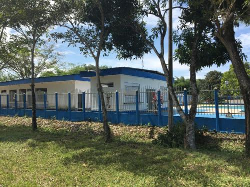 a blue and white building with a fence and trees at Hotel campestre la Maria in Villavicencio