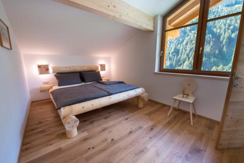 a bedroom with a bed and a large window at Seebacher Apartments in Sarntal