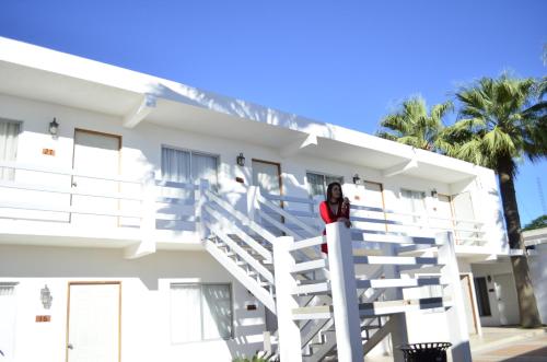 a woman standing on the stairs of a white building at Eco Bay Hotel in Bahía Kino