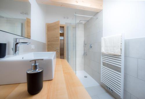 a white bathroom with a sink and a shower at Seebacher Apartments in Sarntal