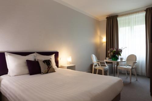 a hotel room with a large bed and a table at Hotel Le Sevigne - Sure Hotel Collection by Best Western in Rennes
