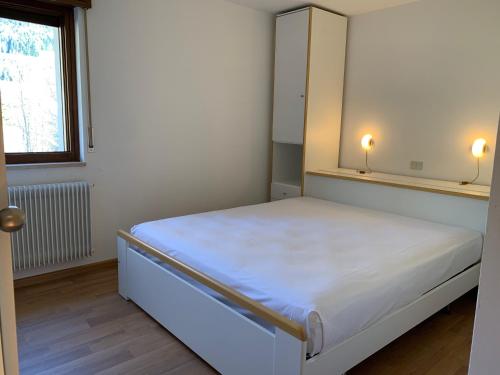 a small bedroom with a bed with two lights on it at Trentino Apartments - Casa Aurora in Folgaria