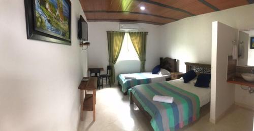 a bedroom with two beds and a table in it at Hotel campestre la Maria in Villavicencio