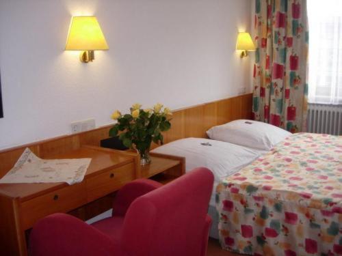ジンデルフィンゲンにあるHotel Kroneのベッド、デスク、椅子が備わるホテルルームです。