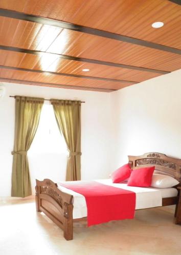 a bedroom with a large bed with red pillows at Hotel campestre la Maria in Villavicencio