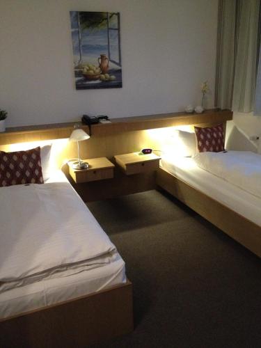 a hotel room with two beds and a lamp at Stadthotel am Bühnenhaus in Kevelaer