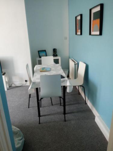 a dining room with a table and white chairs at Belle Vue Bridlington in Bridlington