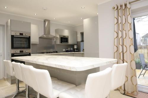 a kitchen with a large white table and white chairs at Oxford Collegiate Serviced Residence by AHG in Oxford
