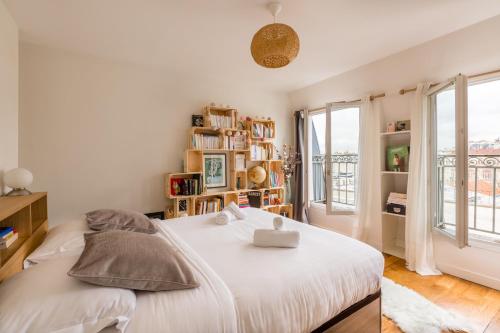 Schlafzimmer mit einem Bett mit weißer Bettwäsche und Fenstern in der Unterkunft Veeve - Rooftop Views By the Canal Saint-Martin in Paris