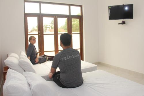 two people sitting on a bed looking out the window at Ever Green Villa in Negombo