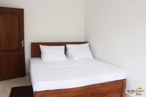 a bed with white sheets and pillows in a room at Ever Green Villa in Negombo