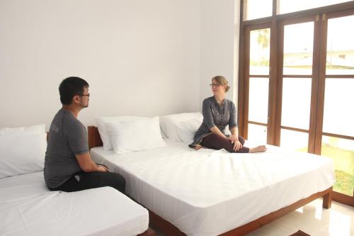 a man and a woman sitting on two beds at Ever Green Villa in Negombo