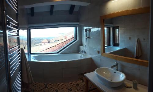 uma casa de banho com uma banheira, um lavatório e uma janela em Wass House em Kosjerić