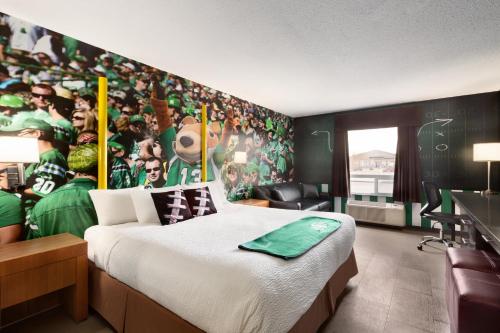 a room with a bed and a wall with a football mural at Days Inn by Wyndham Regina in Regina