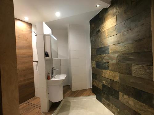 La salle de bains est pourvue d'un lavabo et d'un mur en pierre. dans l'établissement Apartament Centrum, à Olsztyn