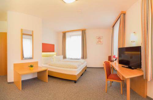 ein Hotelzimmer mit einem Bett, einem Schreibtisch und einem TV in der Unterkunft Hotel Gasthof Stefansbrücke in Innsbruck