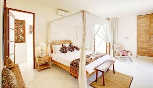 1 dormitorio con cama con dosel y silla en Villa Sahaja, en Canggu
