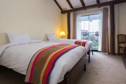 two beds in a hotel room with a window at Luna House Cusco in Cusco