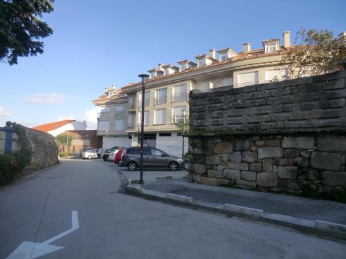 a street with a stone wall and a building at Apartamentos Arosa in Isla de Arosa