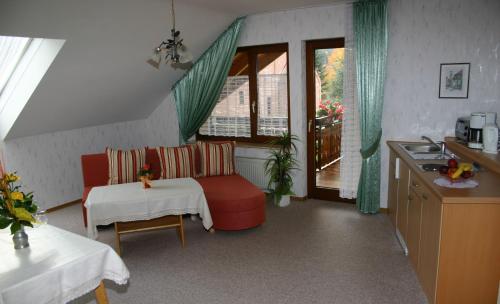 eine Küche mit einem roten Sofa und einem Tisch in einem Zimmer in der Unterkunft Landhaus Enztalperle in Enzklösterle