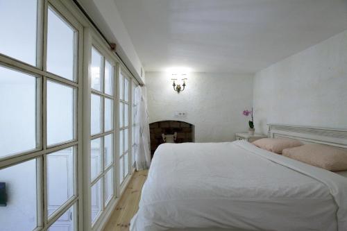 a white bedroom with a bed and a fireplace at Provence Home in Vilnius