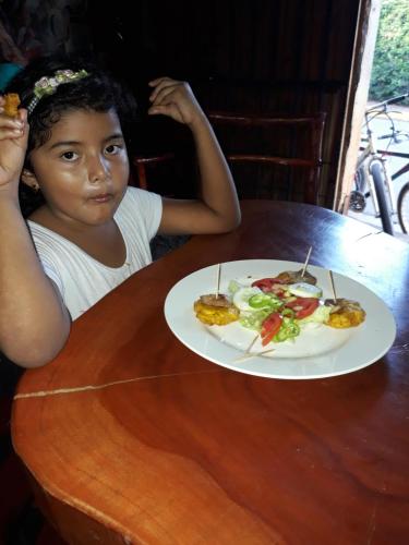 a little girl sitting at a table with a plate of food at Hospedaje Bananas in Altagracia