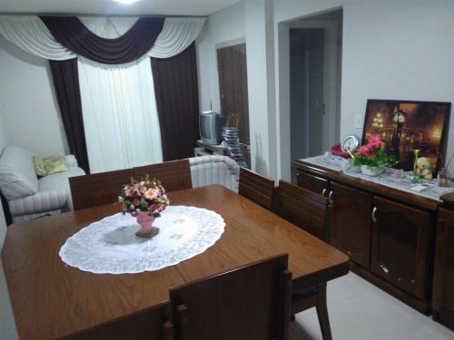 una sala de estar con una mesa con un jarrón de flores. en Residencial Saul Bertemes, en Bombinhas