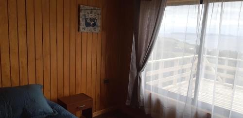 a bedroom with a window with a view of a building at Cabaña Quiquel, Dalcahue, Chiloe in Dalcahue