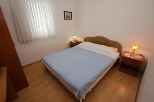 a small bedroom with a bed and two tables at Apartments Bresina in Povljana