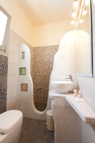 a white bathroom with a sink and a toilet at Alexandra's Rooms in Parikia