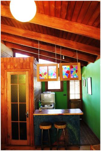 a kitchen with a counter and two stools in it at Cabañas La Magia de Isla Negra in Isla Negra