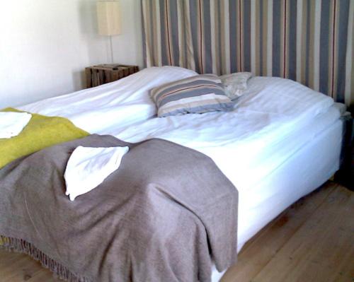 an unmade bed in a bedroom with a striped wall at Elisetorp in Kivik