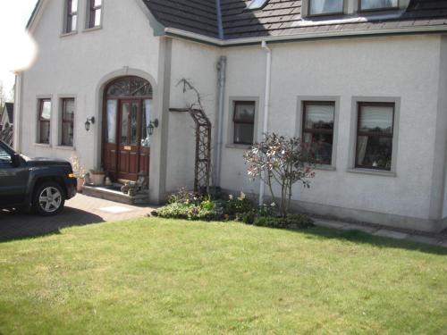 a house with a car parked in front of the door at Narrow Gauge B&B in Ballymoney