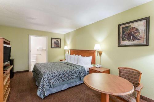 a hotel room with a bed and a table at Days Inn by Wyndham Ormond Beach in Ormond Beach
