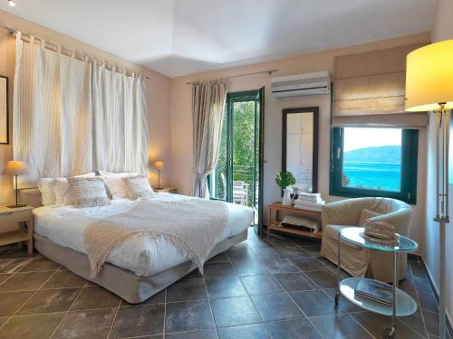 a bedroom with a bed and a chair and a window at Villa Aria - Luxury Beachfront Villa with Pool and Tennis Court in Koilás