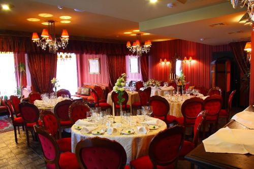 a dining room with tables and chairs and red curtains at Sofijos Rezidencija in Birštonas