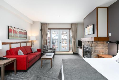 a living room with a red couch and a fireplace at Tour des Voyageurs in Mont-Tremblant