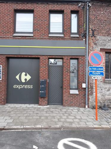 un bâtiment avec un garage et un panneau devant lui dans l'établissement Panda Parc Appartment proche Pairi Daiza-Shape-Nato, à Lens