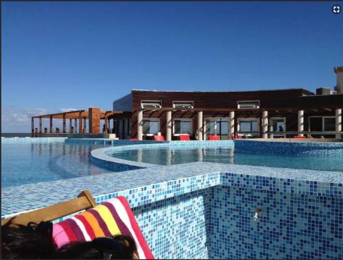 a resort swimming pool with a chair in front of a building at Linda Bay Beach & Resort in Mar de las Pampas