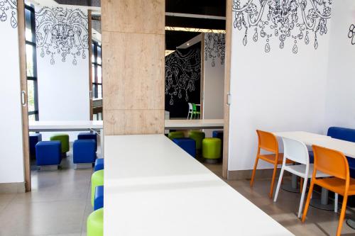 a room with white tables and chairs and blue chairs at ibis budget Manaus in Manaus