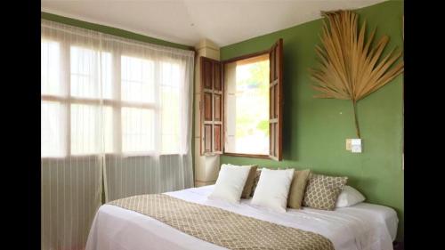 een slaapkamer met groene muren en een bed met kussens bij Beach Front Guesthouse in Puerto Escondido