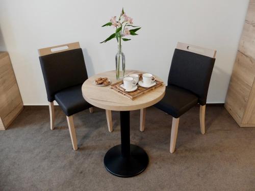 a table with two chairs and a vase with flowers on it at Penzion Stará pošta in Frýdek-Místek