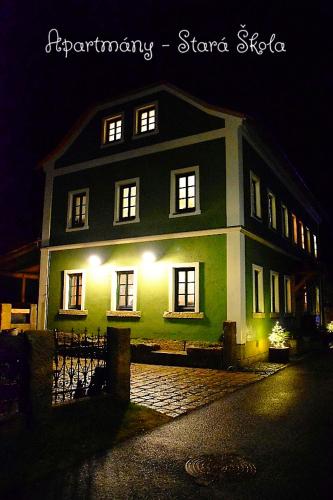 a green and white house with lights on it at Apartmány Stará Škola in Krásná Lípa