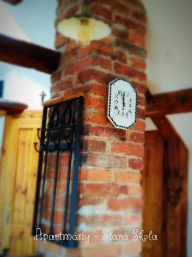 a clock on the side of a brick fireplace at Apartmány Stará Škola in Krásná Lípa
