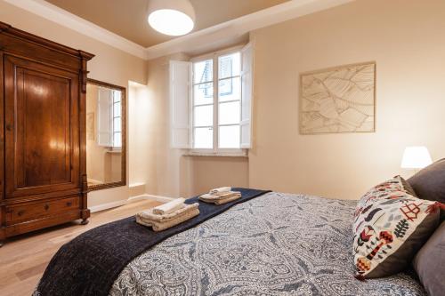 a bedroom with a bed and a wooden cabinet at Suite cuore di Lucca - 2 smart TV - Heart of Lucca in Lucca