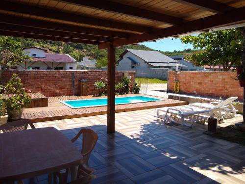 un patio con una mesa y una piscina en Casa em bombinhas - sc, en Bombinhas