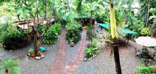 a garden with a brick pathway with plants and trees at Hotel Tropical Sands Dominical in Dominical