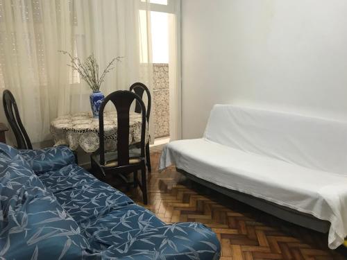 Habitación con 2 camas, mesa, mesa y sillas. en Apartamento Copacabana 876, en Río de Janeiro