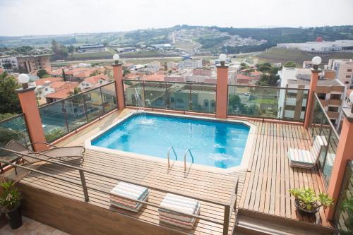 a deck with a swimming pool on top of a building at Grand Enio Hotel e Cantina in Varginha